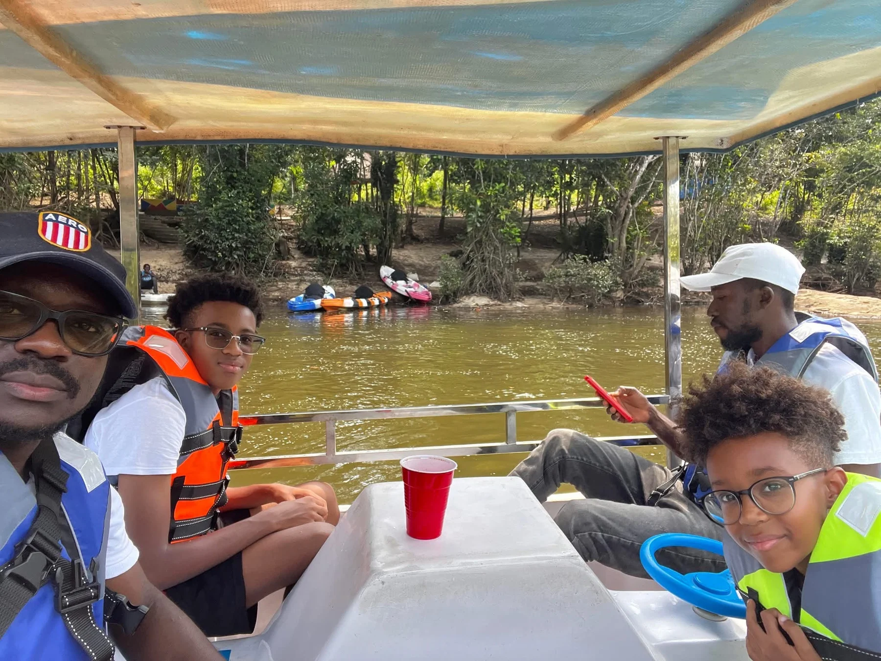Visitors enjoying a boat outing beside the wooded riverbank